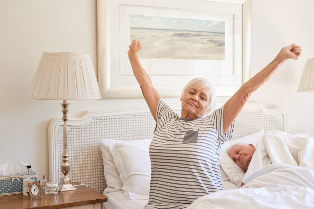 Une femme senior heureuse qui s'étire et bâille à son réveil